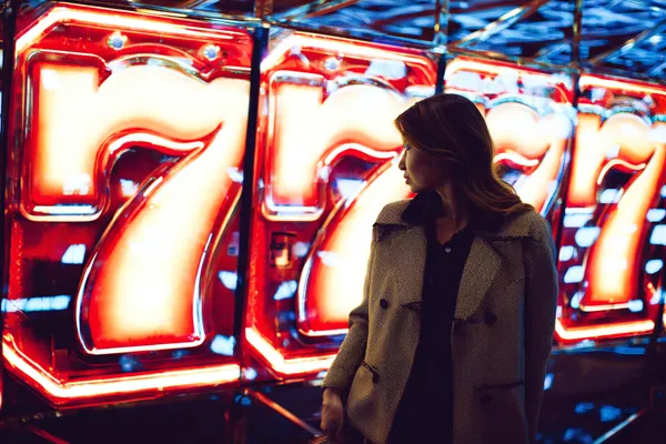 777ZK Games — Explore our rich library of casino classics A woman smiling while playing online games on her laptop, surrounded by neon casino elements, showcasing 777ZK’s diverse game collection.